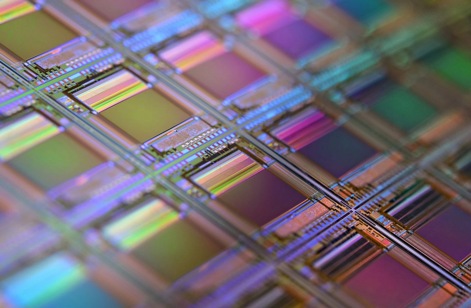 Microscopic circuits and iridescent chip dies arranged on a silicon wafer